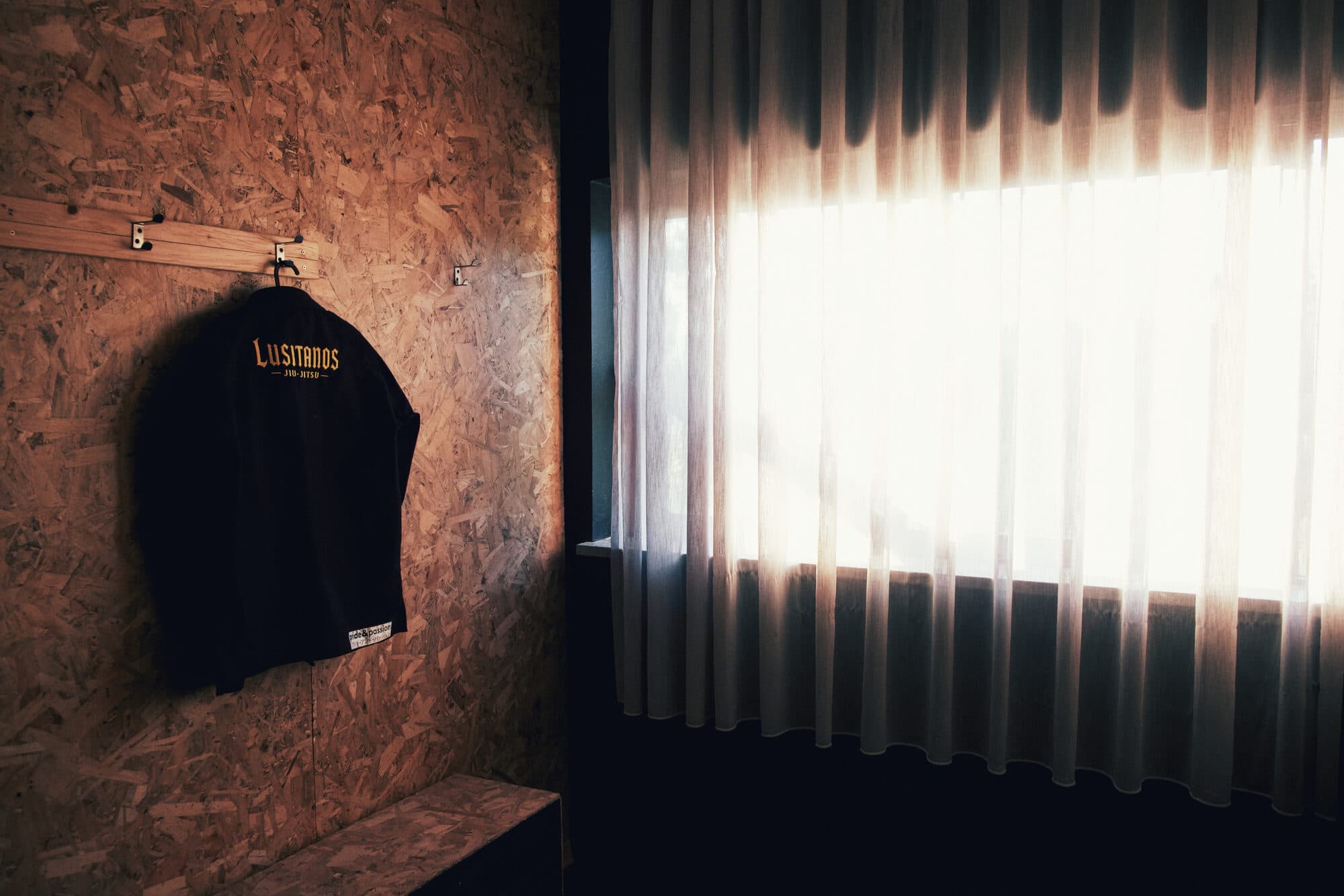 Kimono da Lusitanos Jiu-Jitsu pendurado junto à janela do dojo, em Viseu